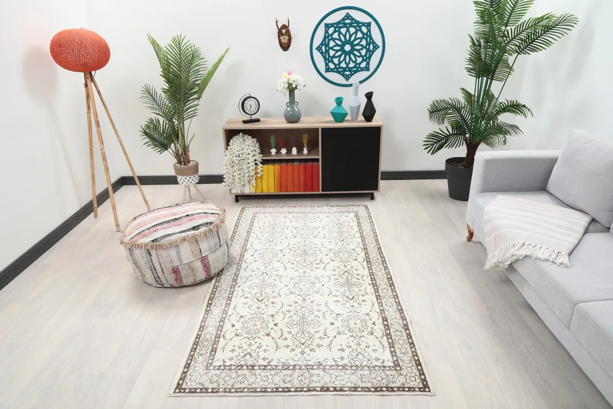 Ivory and brown vintage rug placed in a modern living room setting with light wood floors.