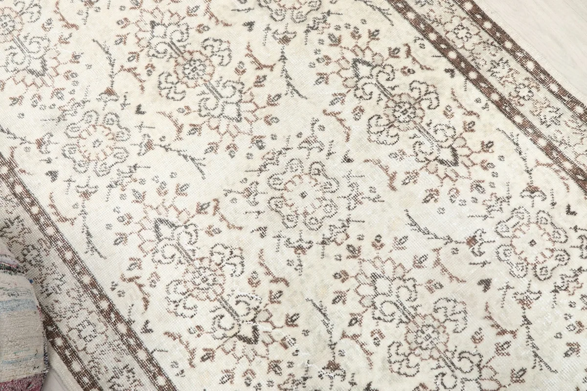 Overhead close-up of the rug's central design, revealing the faded brown floral and geometric motifs.