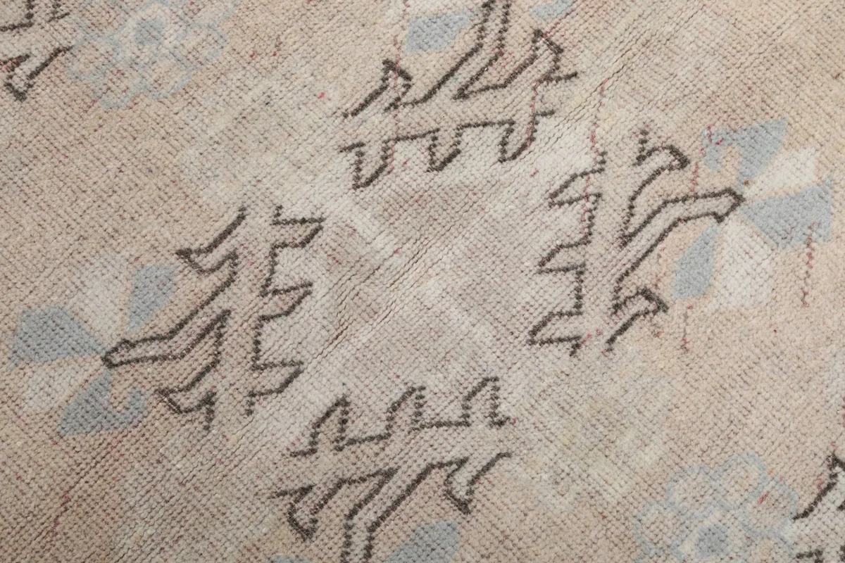 Detailed view of a single geometric medallion motif on the rug's beige field