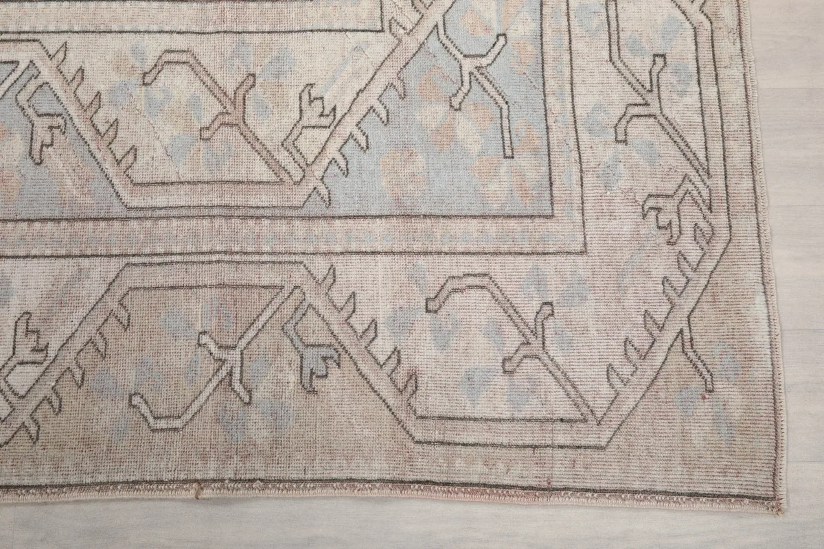 Detail of the rug's outer border with geometric designs and a gray outline