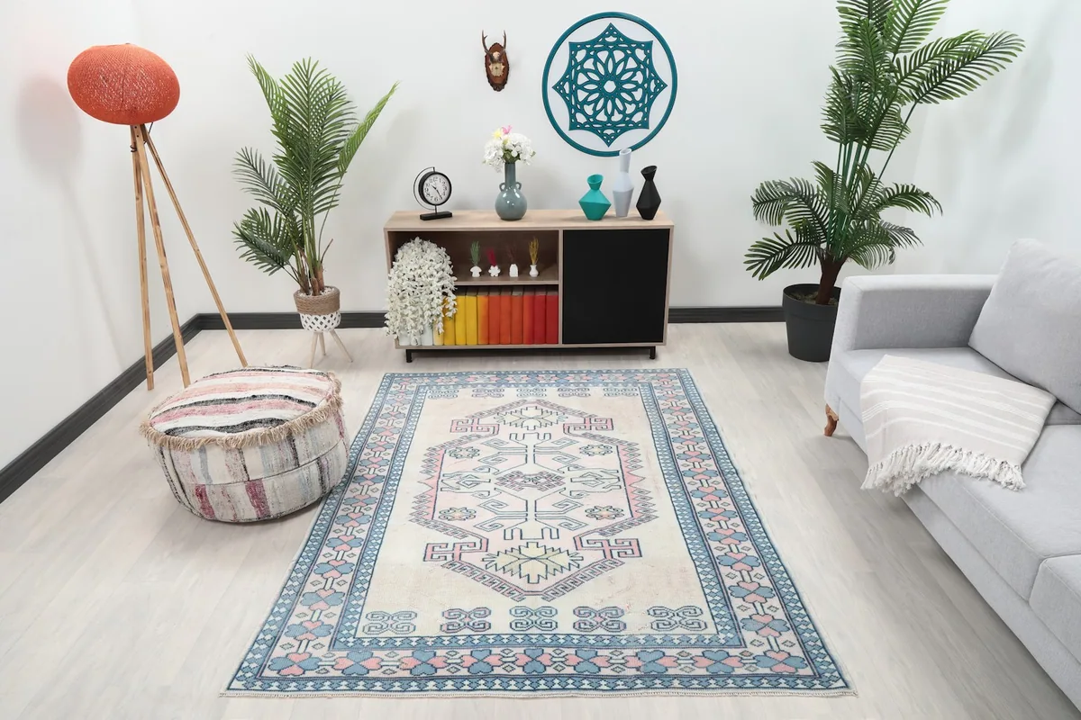 Ivory blue pink rug displayed in a bright room setting with a light gray sofa
