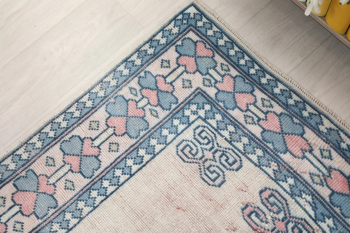 Corner detail of the rug's border with repeated blue and pink geometric elements