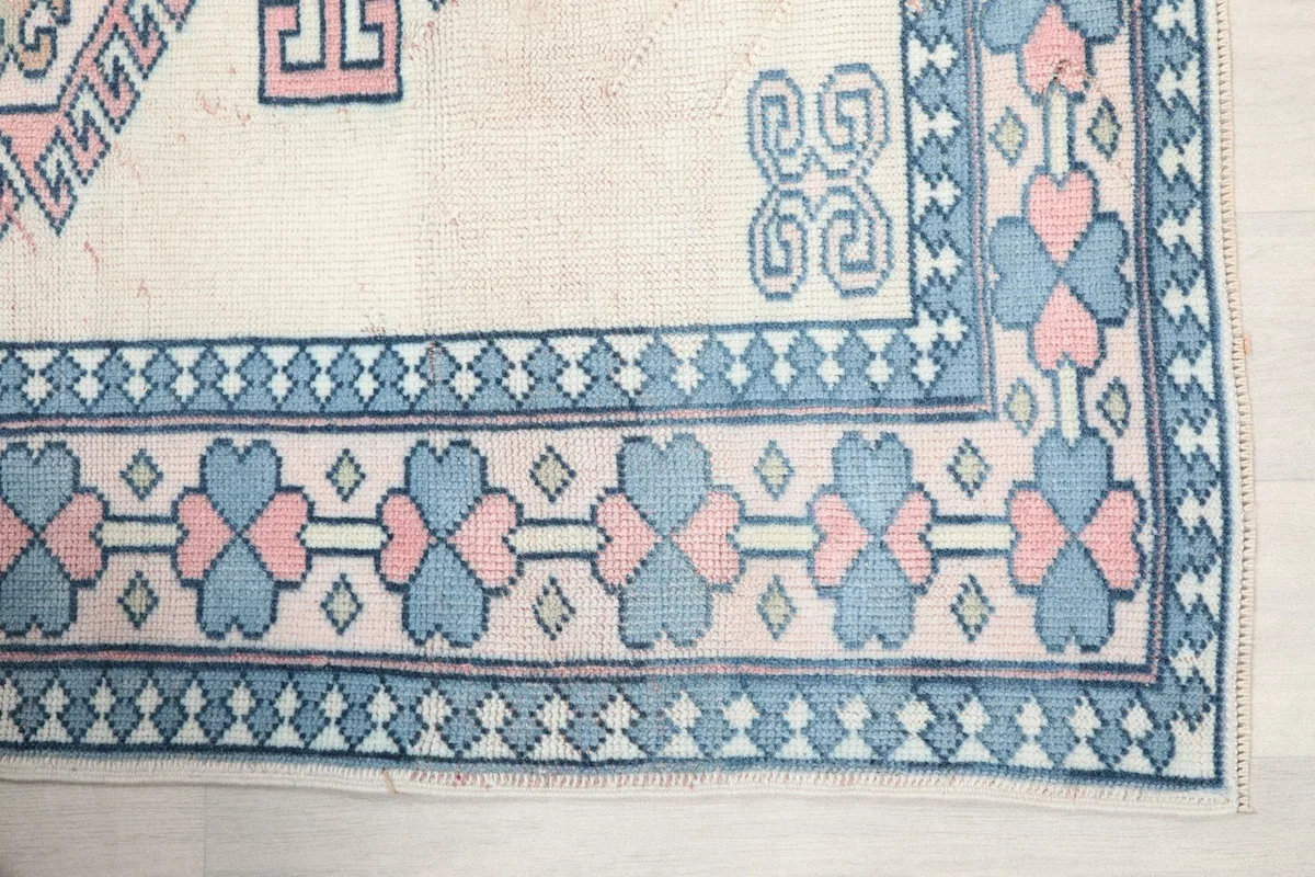 Detail of the rug's blue and pink heart-shaped border motifs on an ivory field