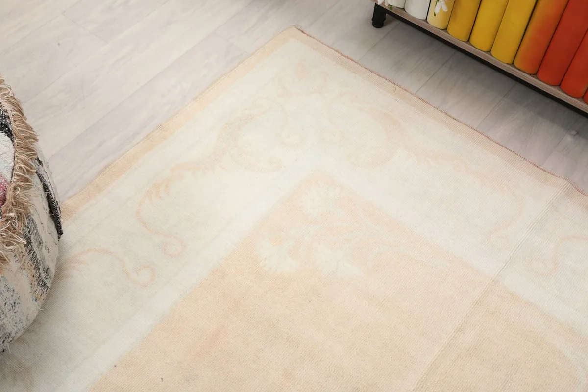Corner view of the rug's border and field, highlighting the faded beige tones