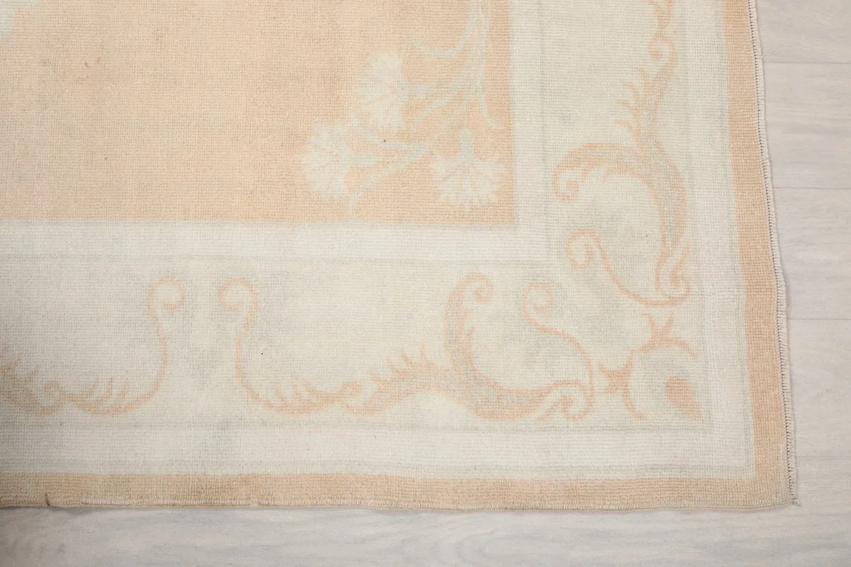 Detailed view of the ivory scrollwork and motifs within the rug's border
