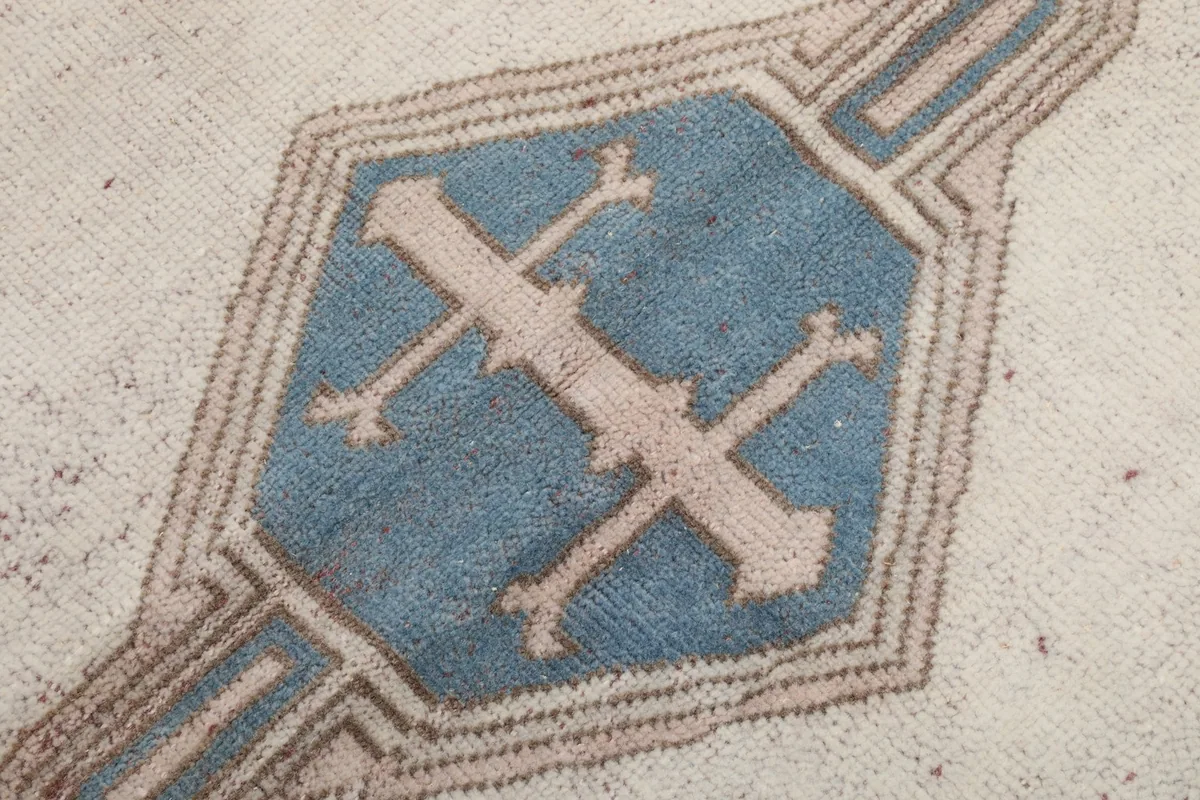 Close-up detail of one central blue tribal geometric motif on the rug's ivory field