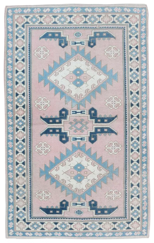 Full top view of a pink and blue geometric vintage Anatolian area rug on a white background