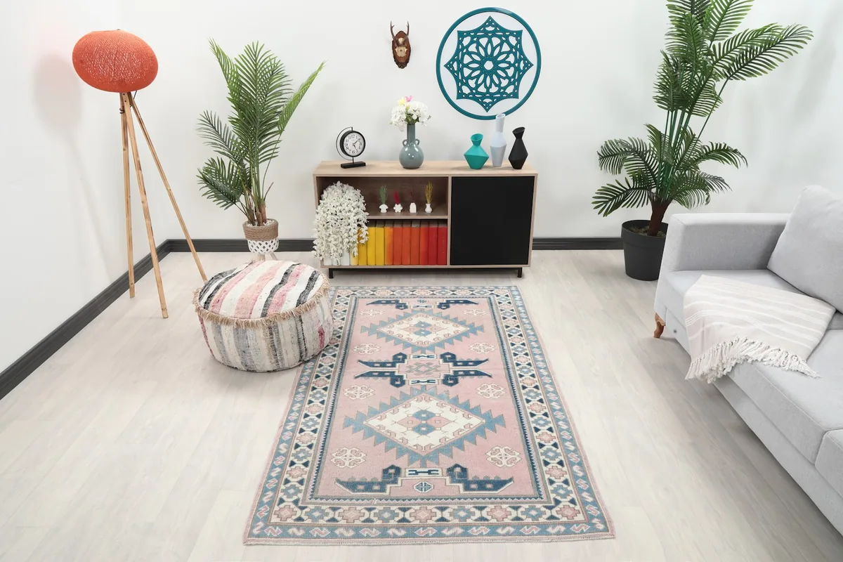 Pink and blue geometric area rug placed in a modern living room setting with light furniture