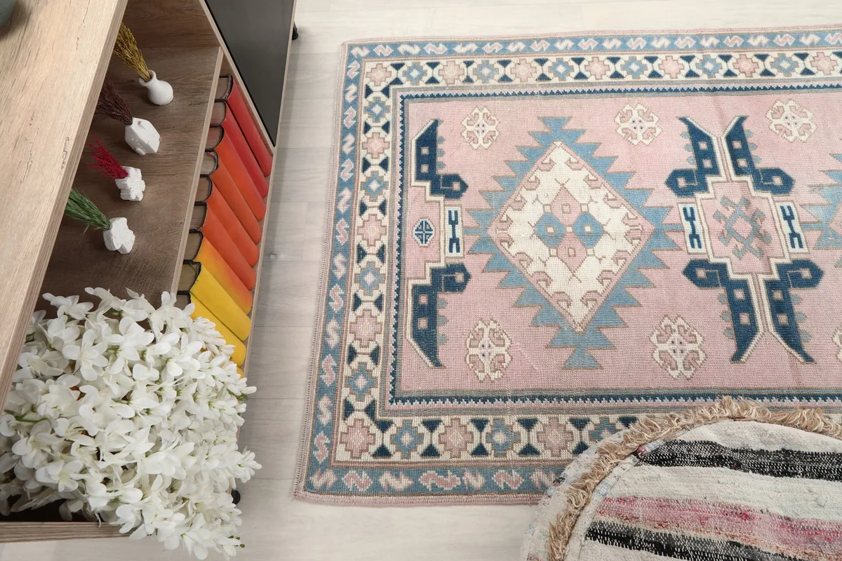 Top-down view of the rug in a room setting, with part of a bookshelf and ottoman visible