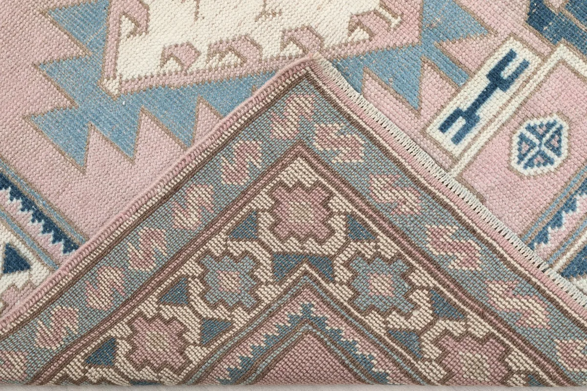View of the back of the rug, folded to show the hand-knotted cotton foundation and wool pile