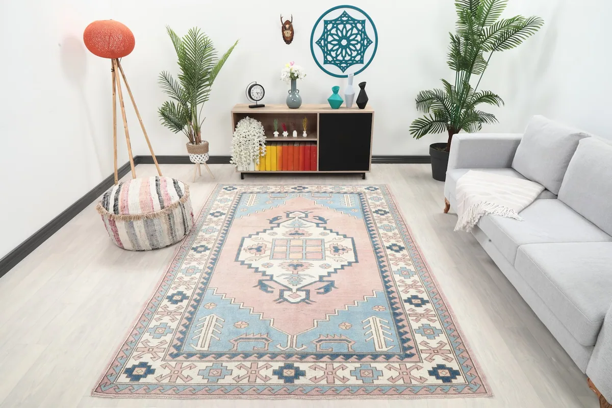 Vintage pink and blue rug displayed in a modern living room setting with a light gray sofa