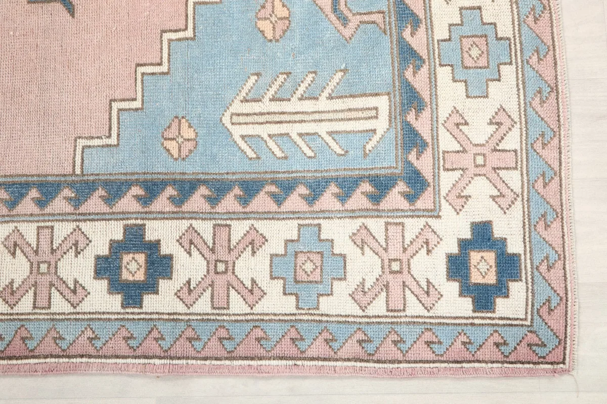 Detailed view of the corner of the rug, highlighting the blue and ivory geometric border motifs