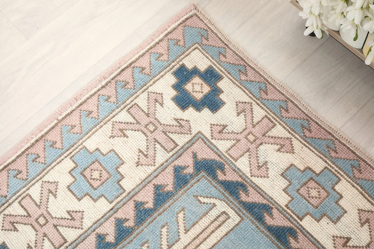 Corner detail of the rug's border, showcasing the navy and pink geometric patterns