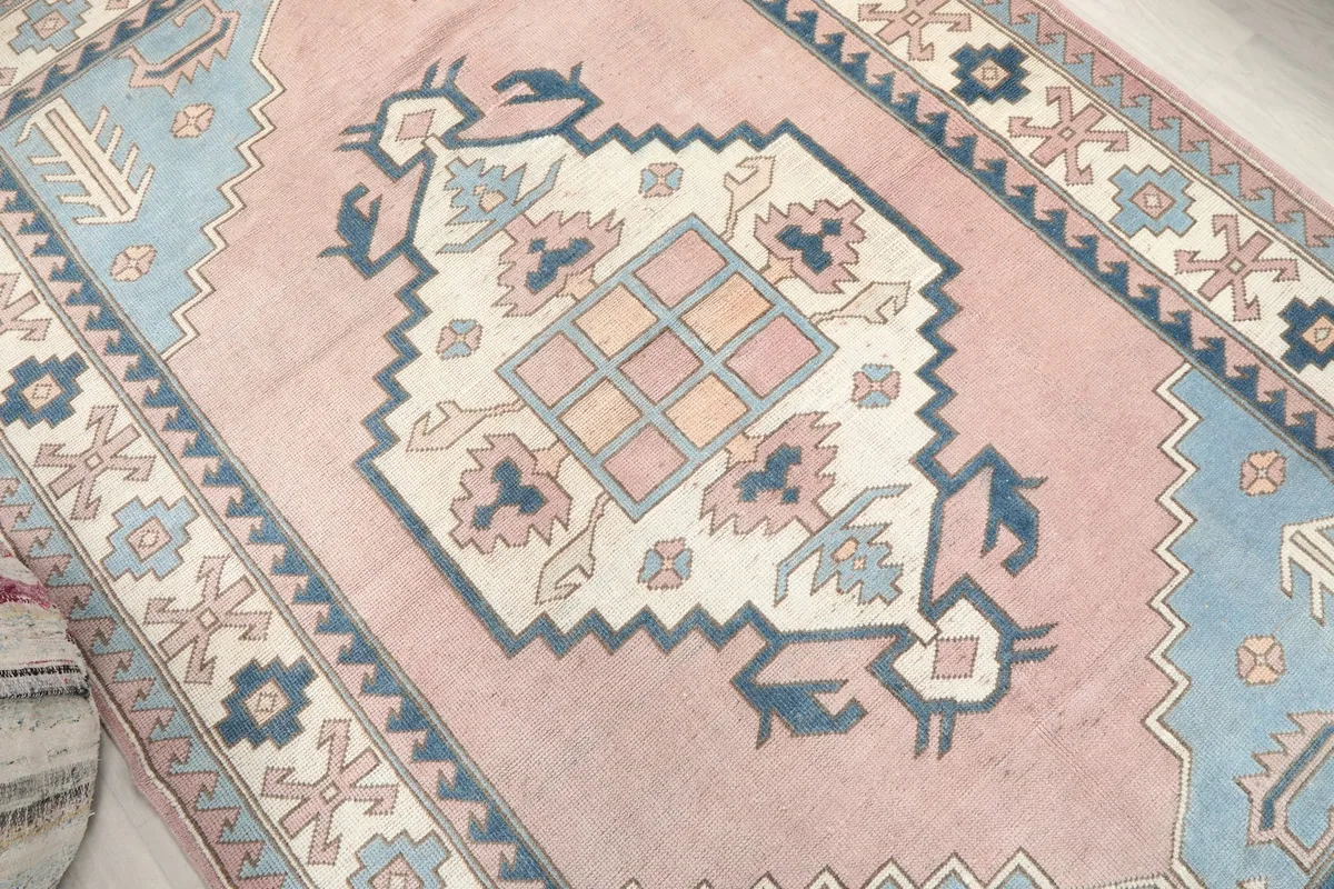 Overhead view of the rug's center, focusing on the intricate pink, blue, and ivory medallion design