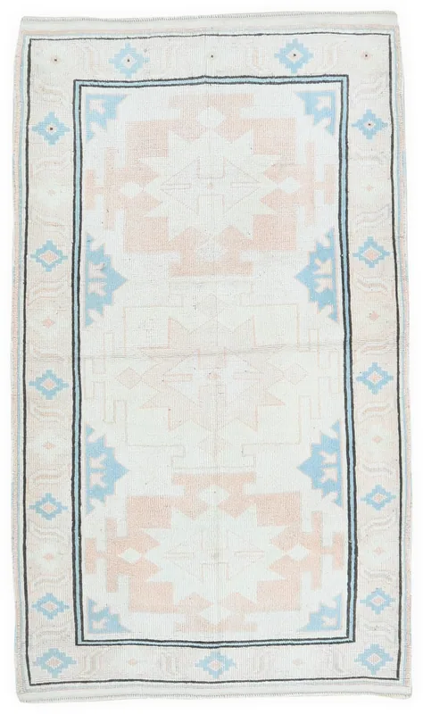 Full top view of the ivory, rose, and blue geometric vintage Anatolian rug.