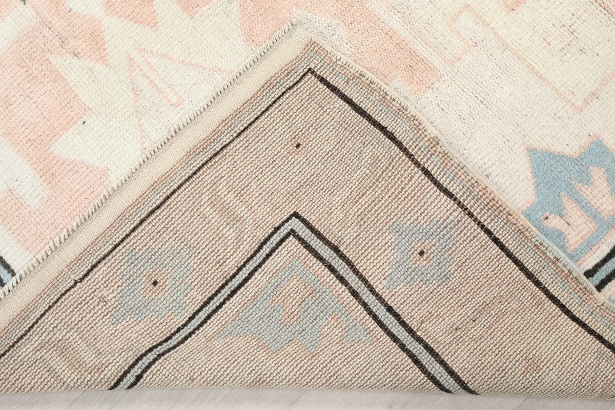 Underside view of the rug corner, showing the cotton foundation and knotting.