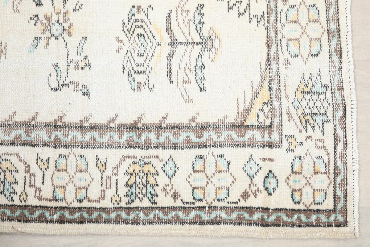 Close-up of the Ivory Tribal Medallion Rug's border and corner motifs in blue, tan, and gray.