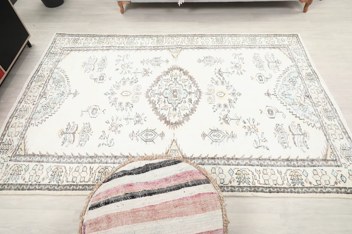 Ivory Tribal Medallion Rug in a room setting, with a striped pouf in the foreground.