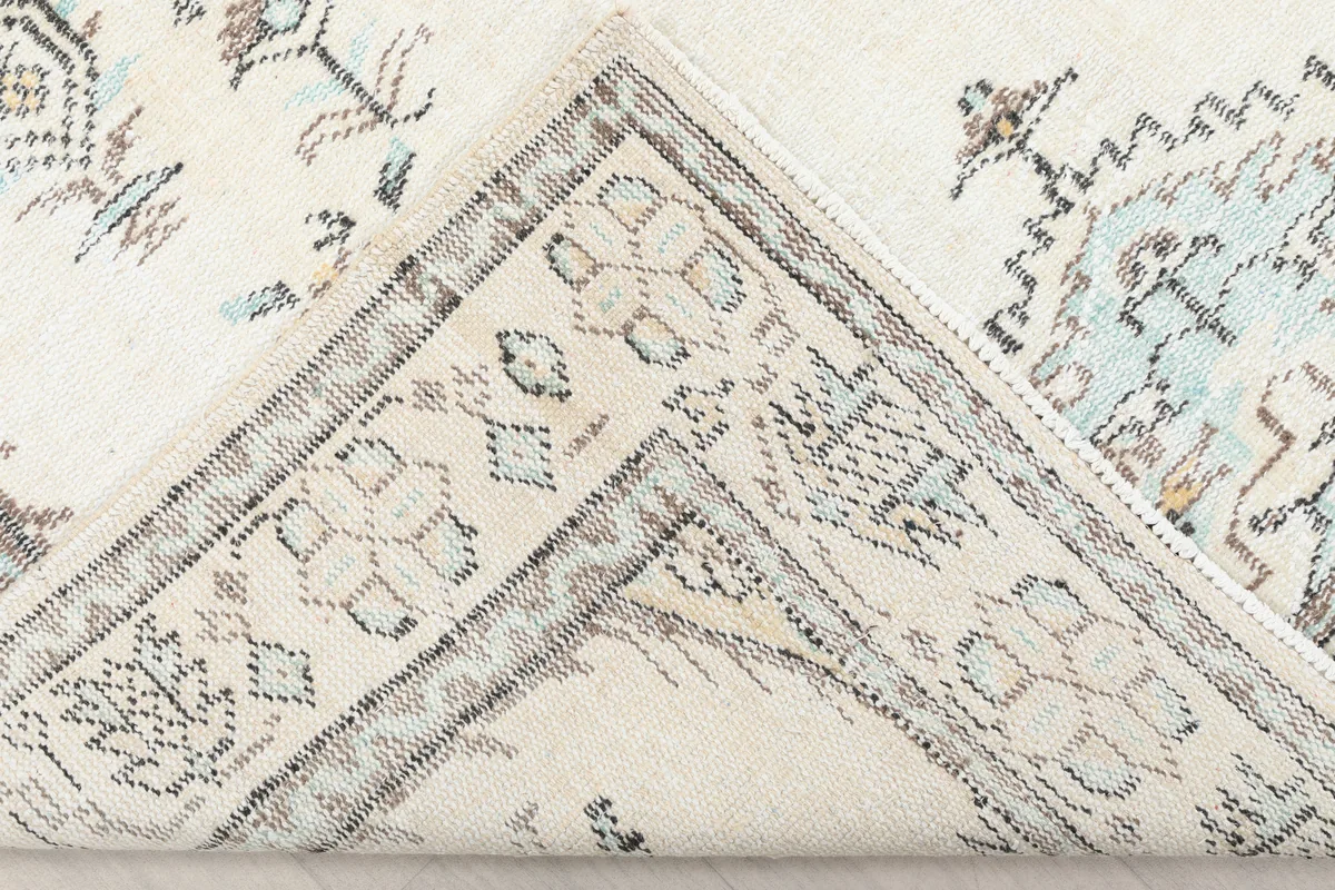 Ivory Tribal Medallion Rug's corner folded back, revealing the rug's construction.