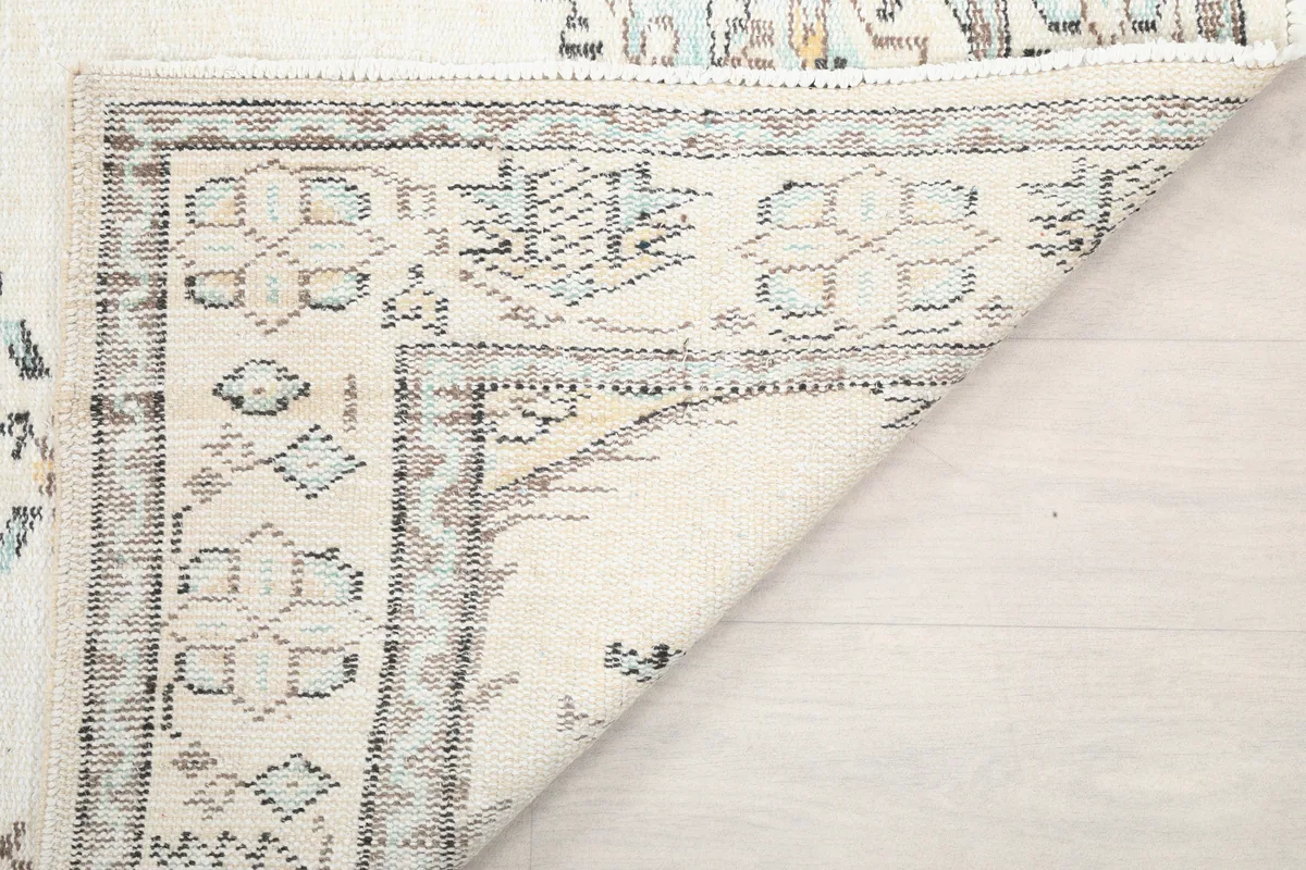 Ivory Tribal Medallion Rug's corner folded to show the reverse side and knotting detail.