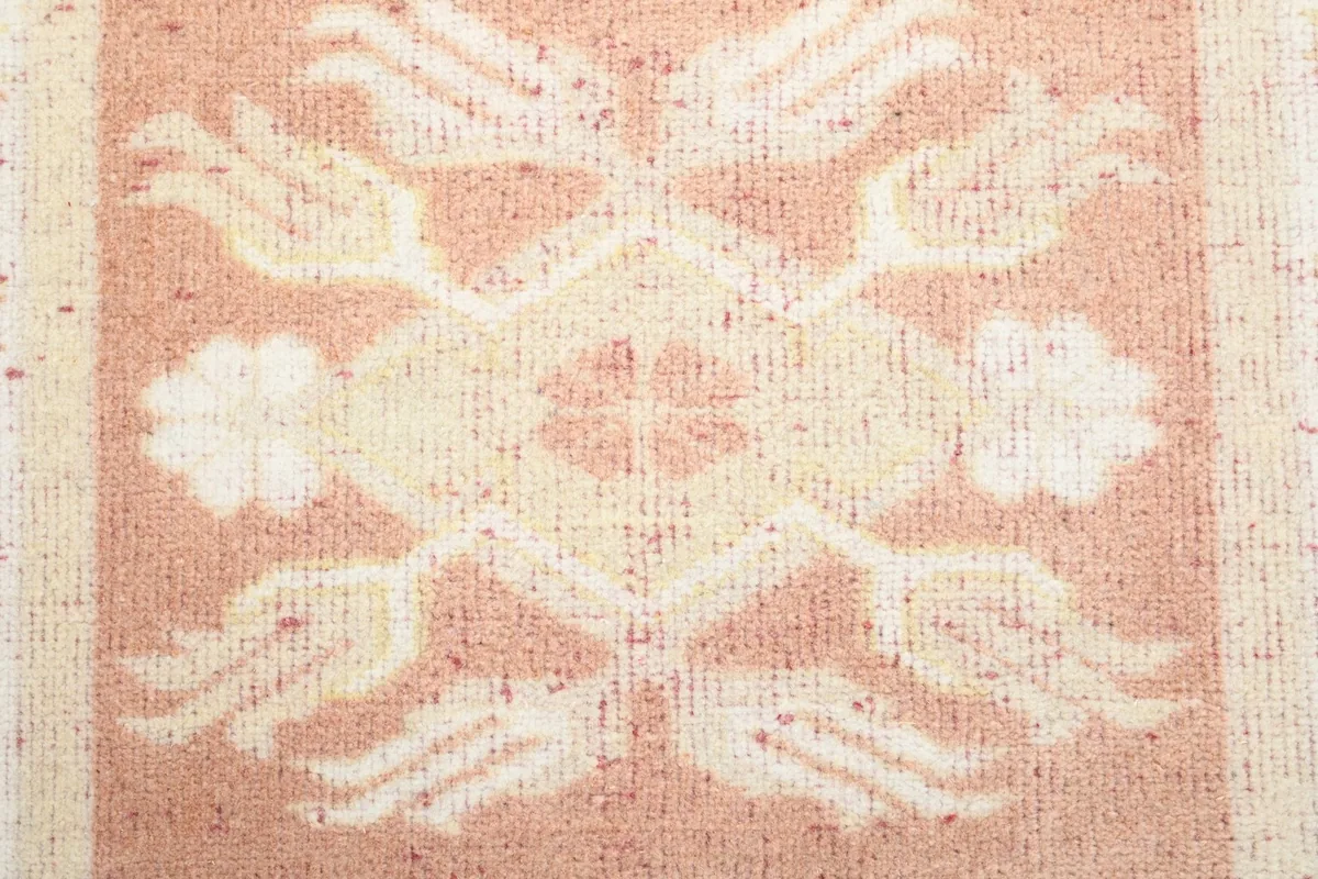 Macro view of a central motif on the pink field, highlighting the low pile texture and color variations