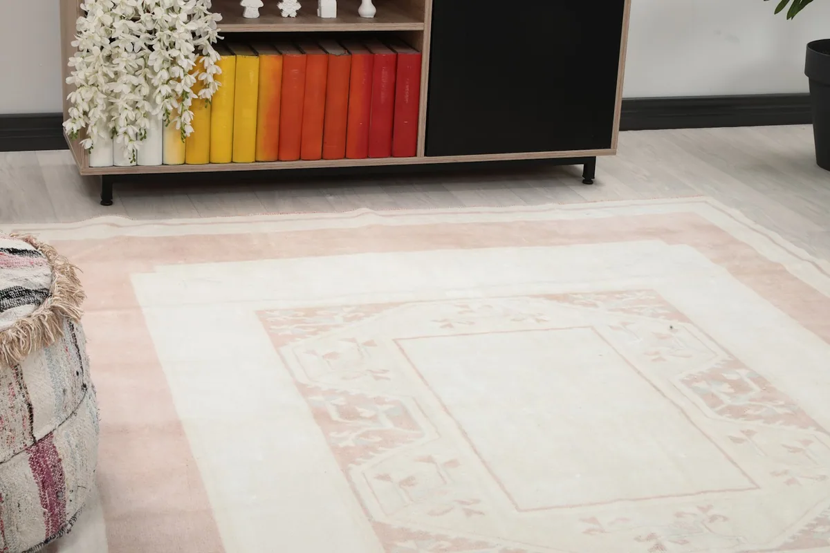 Close-up view of the rug's ivory field and a section of the pink border in a room setting