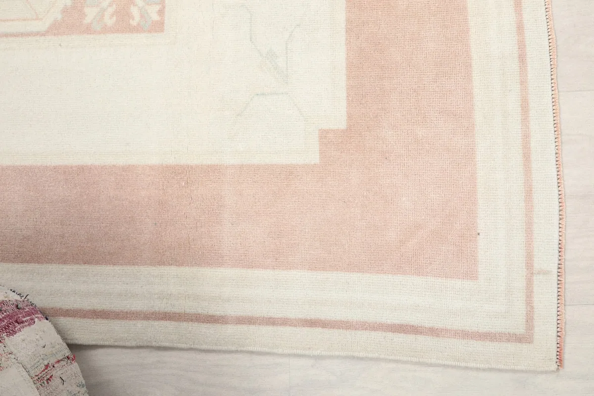 Detailed view of the rug's outer pink border and inner ivory lines