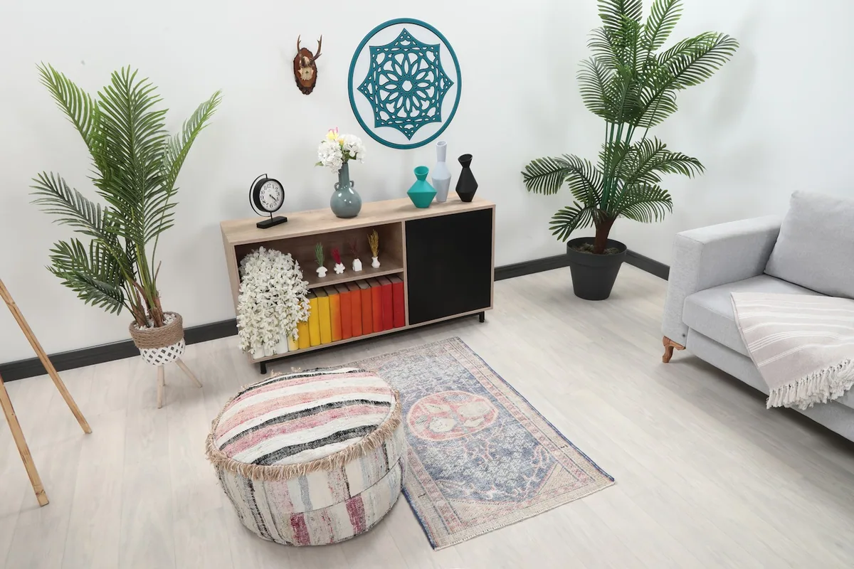 Angle view of the rug in a room setting, showing its size relative to a pouf and cabinet.