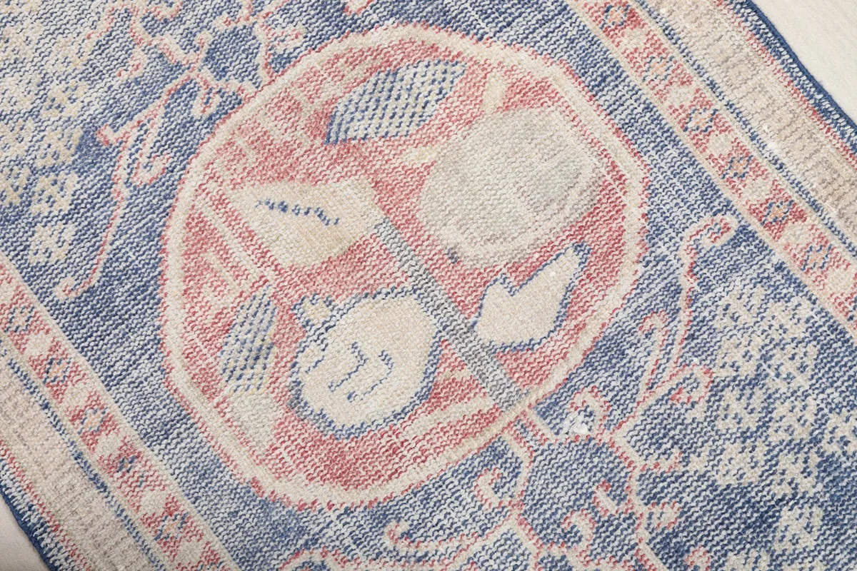 Close-up of the central rose medallion with stylized cream and blue floral motifs.