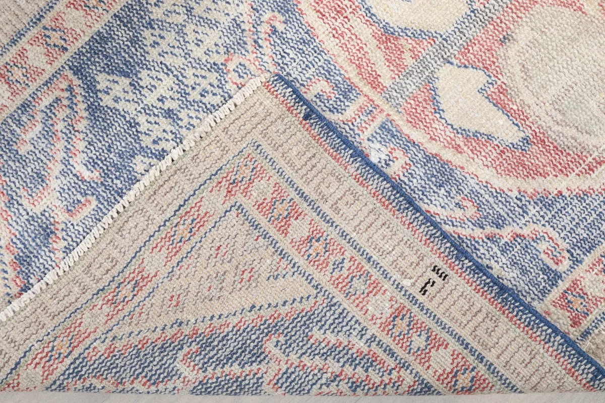 View of the rug's reverse side, showing the hand-knotted cotton foundation and wool knots.