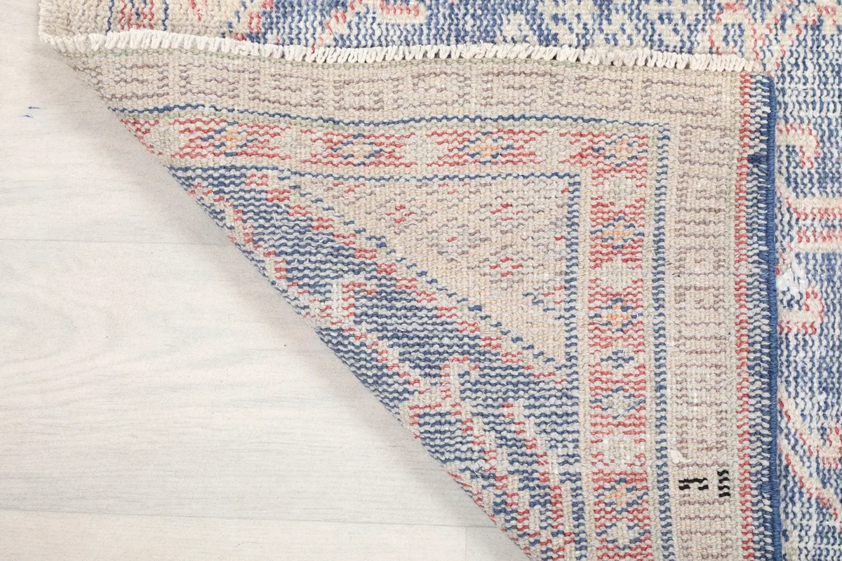 Corner of the rug folded back, revealing the weave and construction of the reverse side.