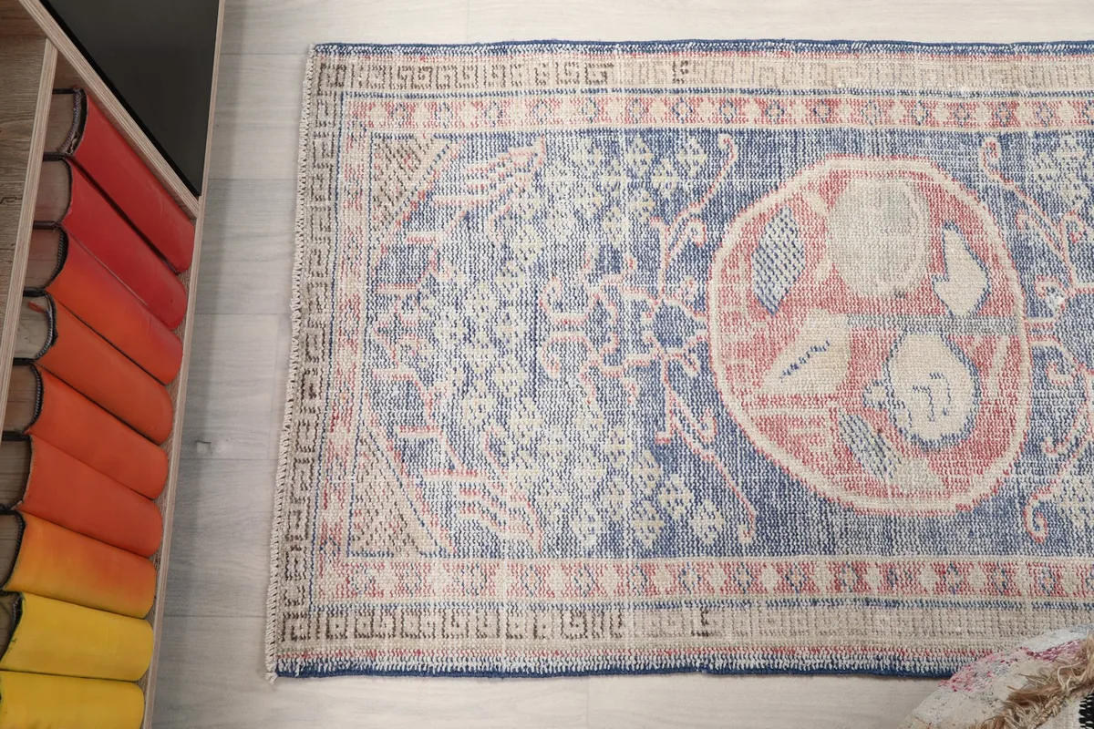 Overhead shot of the rug, slightly angled, with a colorful bookshelf in the background.