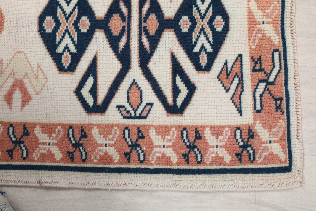 Detailed view of the Ivory Geometric Anatolian Runner's border and central navy and orange geometric motifs.
