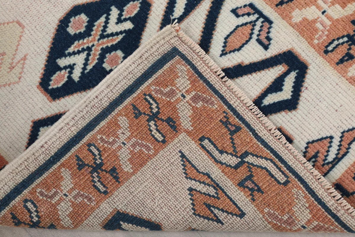 Folded corner of the Ivory Geometric Anatolian Runner, revealing the back of the rug and the tight knotting.