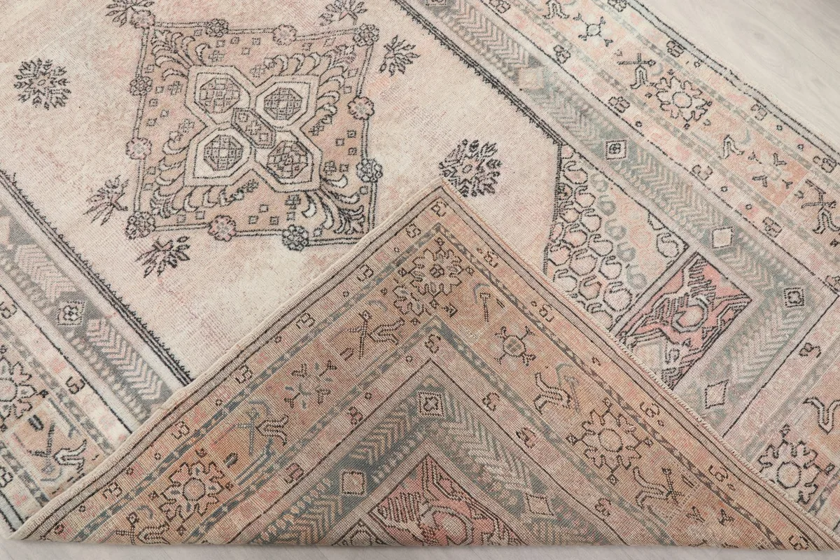 Corner of the rug folded back, revealing a glimpse of the underside and knotting