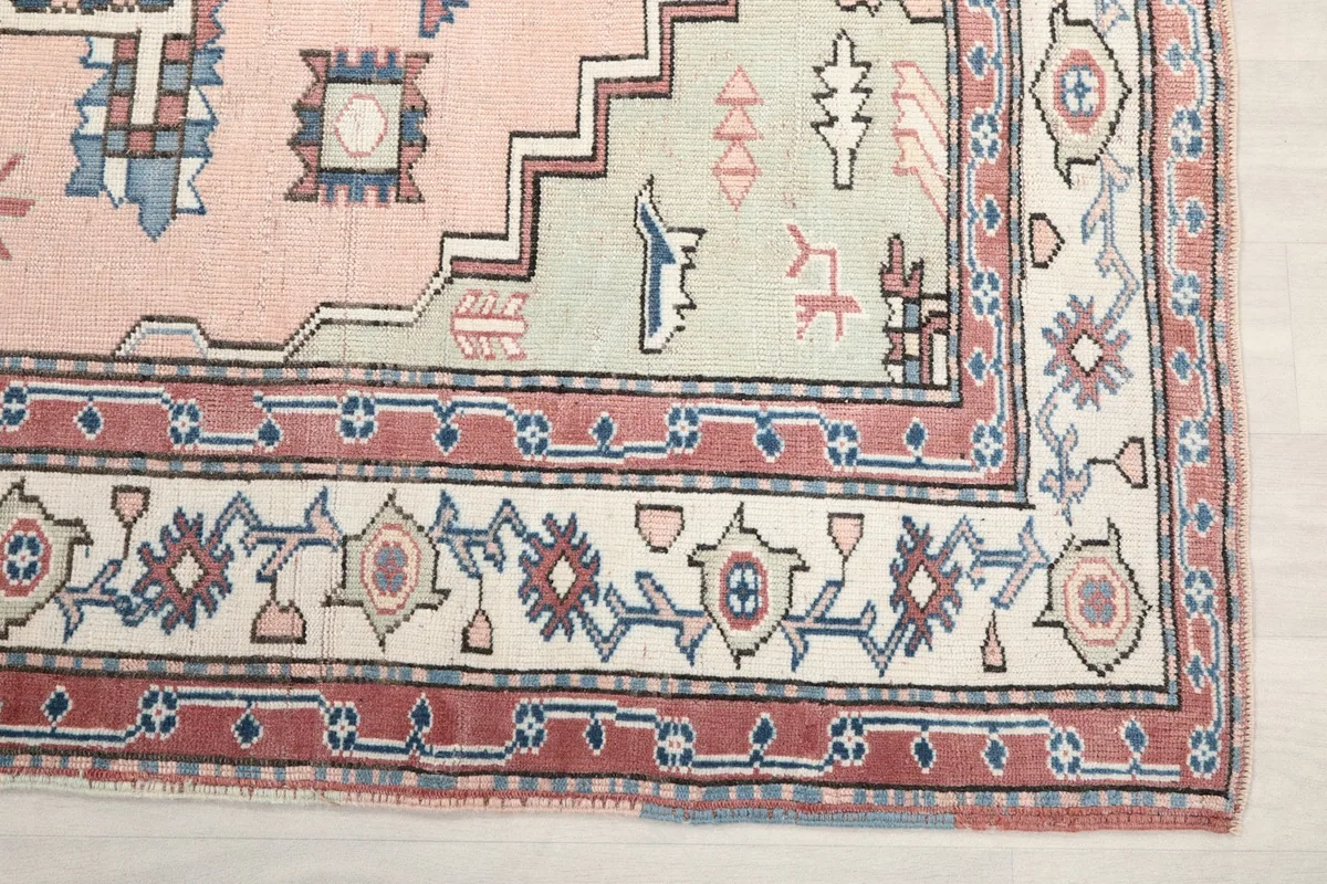 Detail of the rug's border pattern, featuring red, blue, and ivory geometric motifs.
