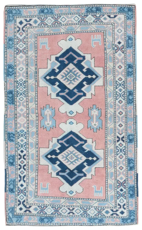 Top view of the pink and navy geometric vintage Anatolian rug on a white background.