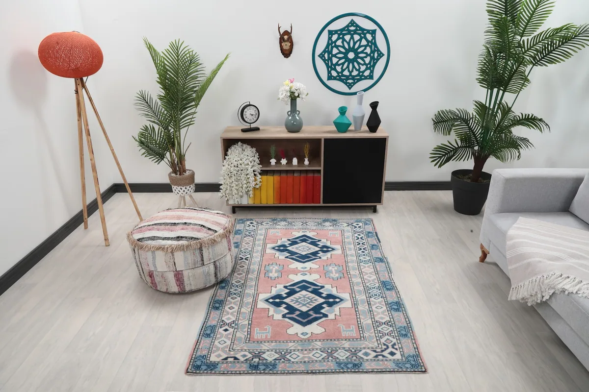 Small pink and navy geometric rug placed in a modern living room setting with a light gray couch.