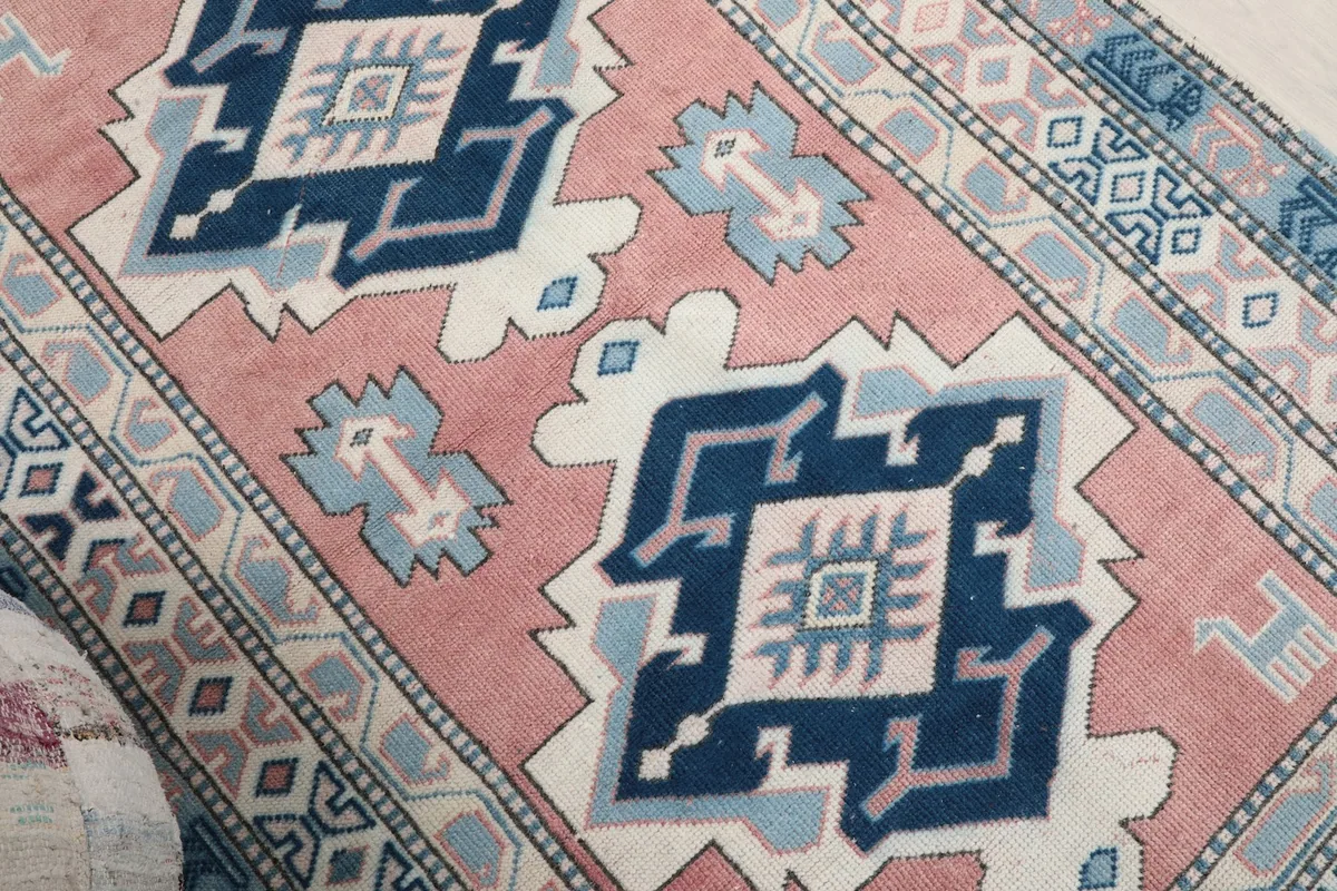 Detailed view of the central navy and light blue geometric medallion on the pink rug.