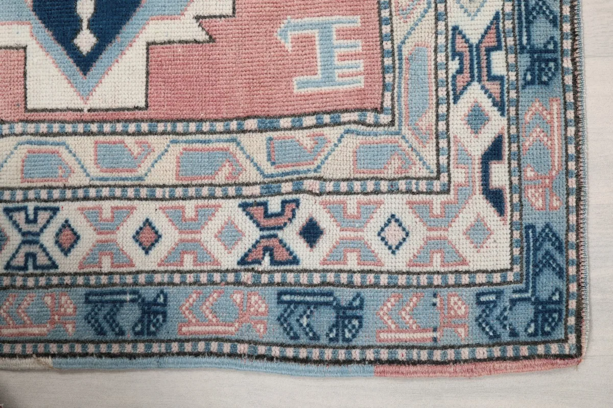 Detail of the light blue and ivory border with intricate geometric designs on the vintage rug.