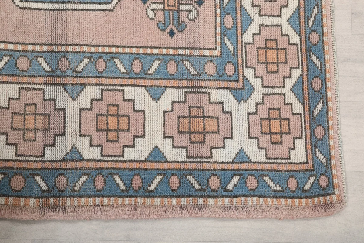 Detail of the rug's corner, highlighting the blue and beige geometric border patterns