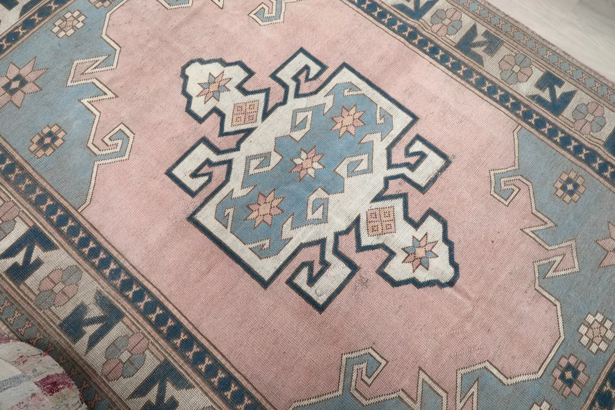 Angled view highlighting the central blue and ivory medallion on the pink background