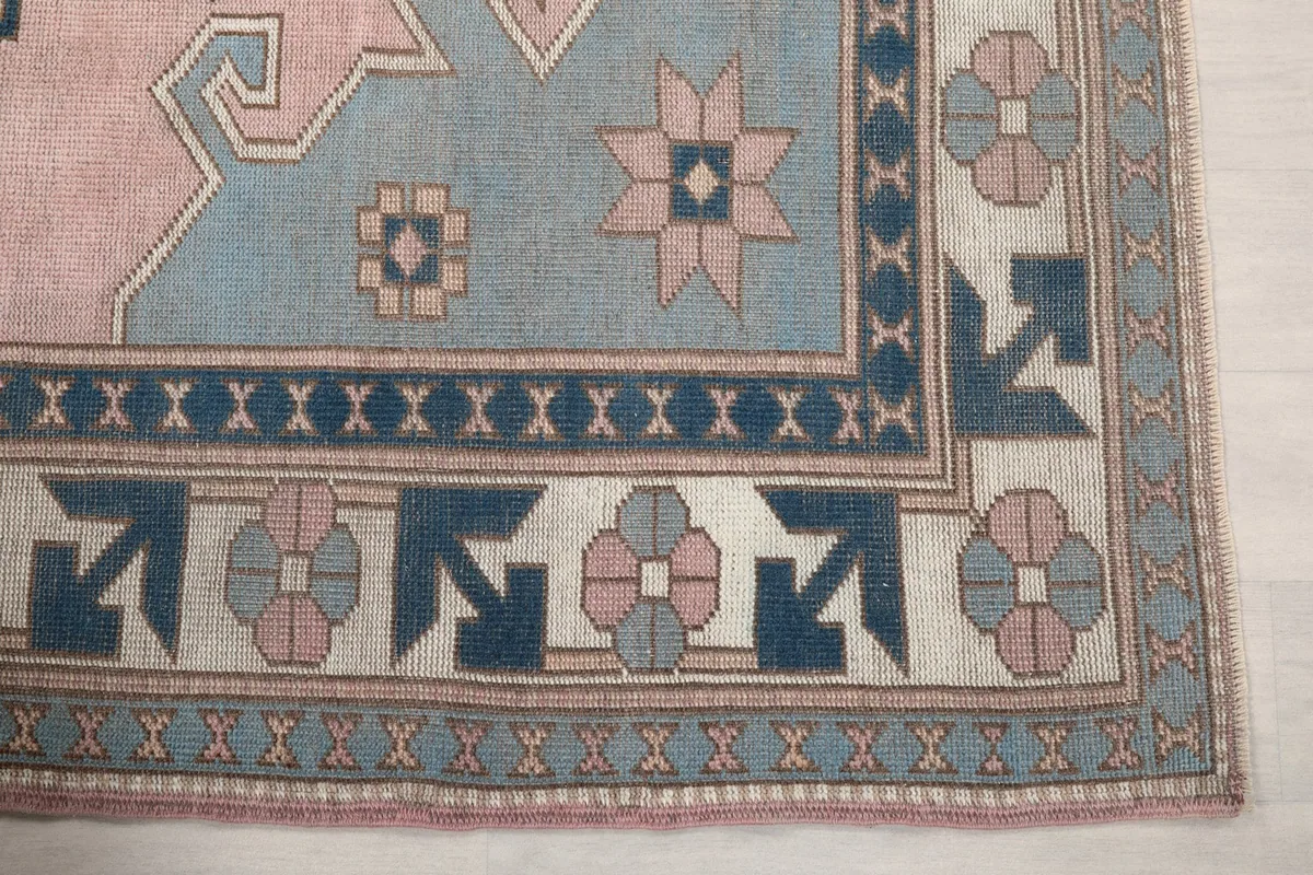 Detailed view of the rug's border design featuring navy geometric motifs and pink flowers