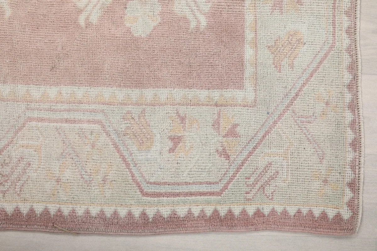 Detail of the geometric border design and corner of the vintage pink and beige rug