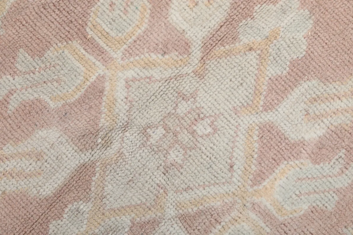 Close-up of the low wool pile and hand-knotted texture of the pink and beige rug
