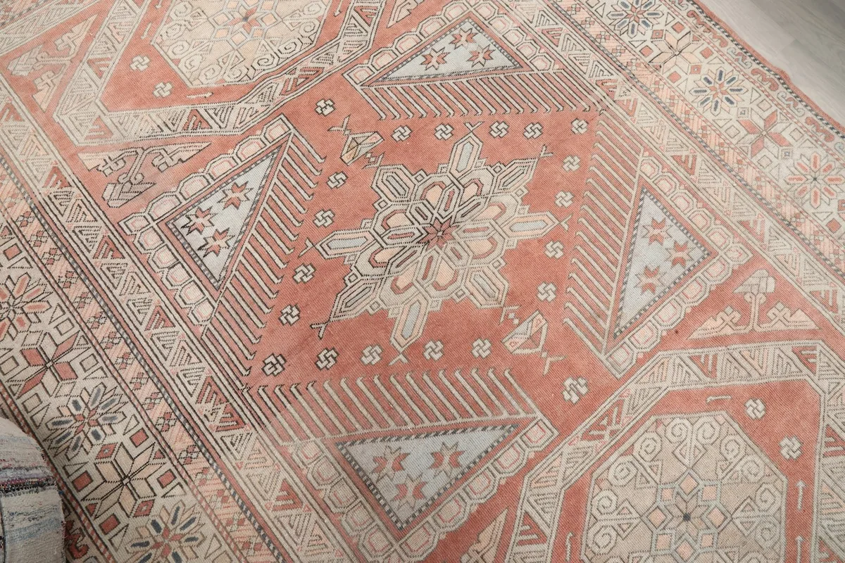 Angled detail shot of the central medallion and surrounding geometric patterns in rust and beige