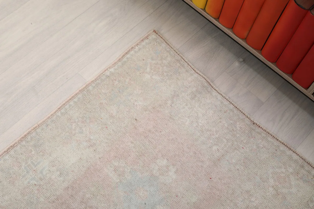 Detail of the rug's edge and subtle border design next to a piece of furniture