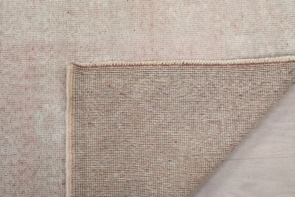 Corner of the rug folded to show the hand-knotted construction on the back