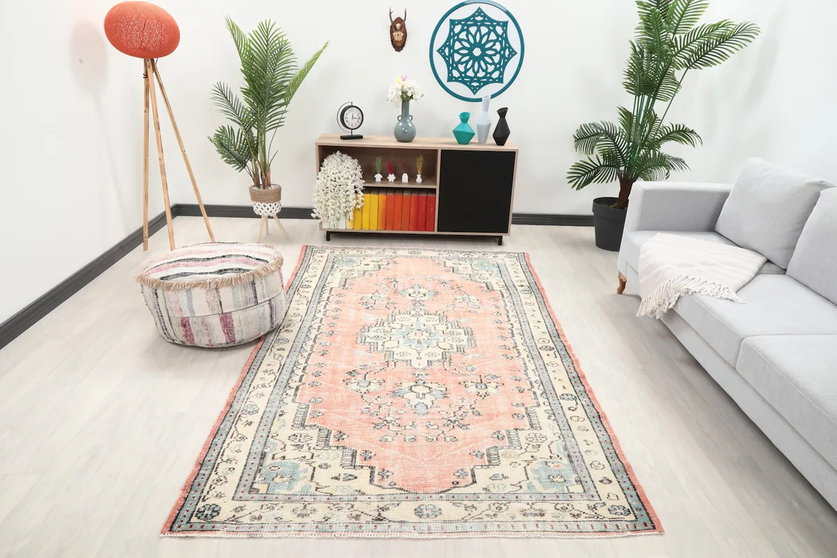 Vintage Anatolian rug with rose field and ivory border placed in a modern living room setting.