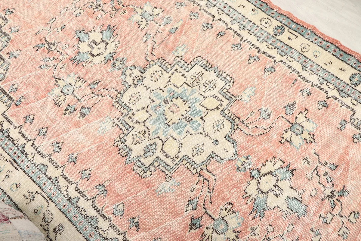Close-up of the central medallion and floral elements in blue and ivory on the rose field.